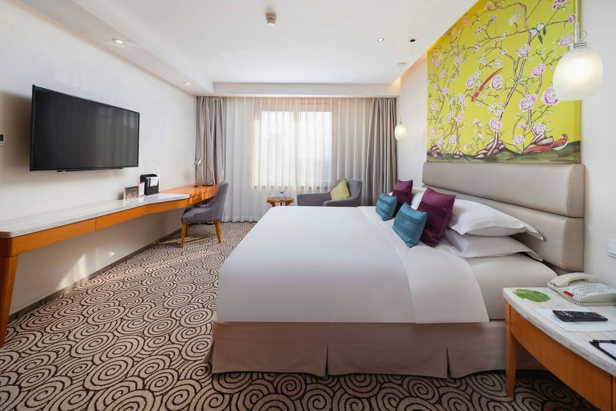 Une chambre d’hôtel avec un lit, un bureau, une chaise, une télévision et un tableau au mur.