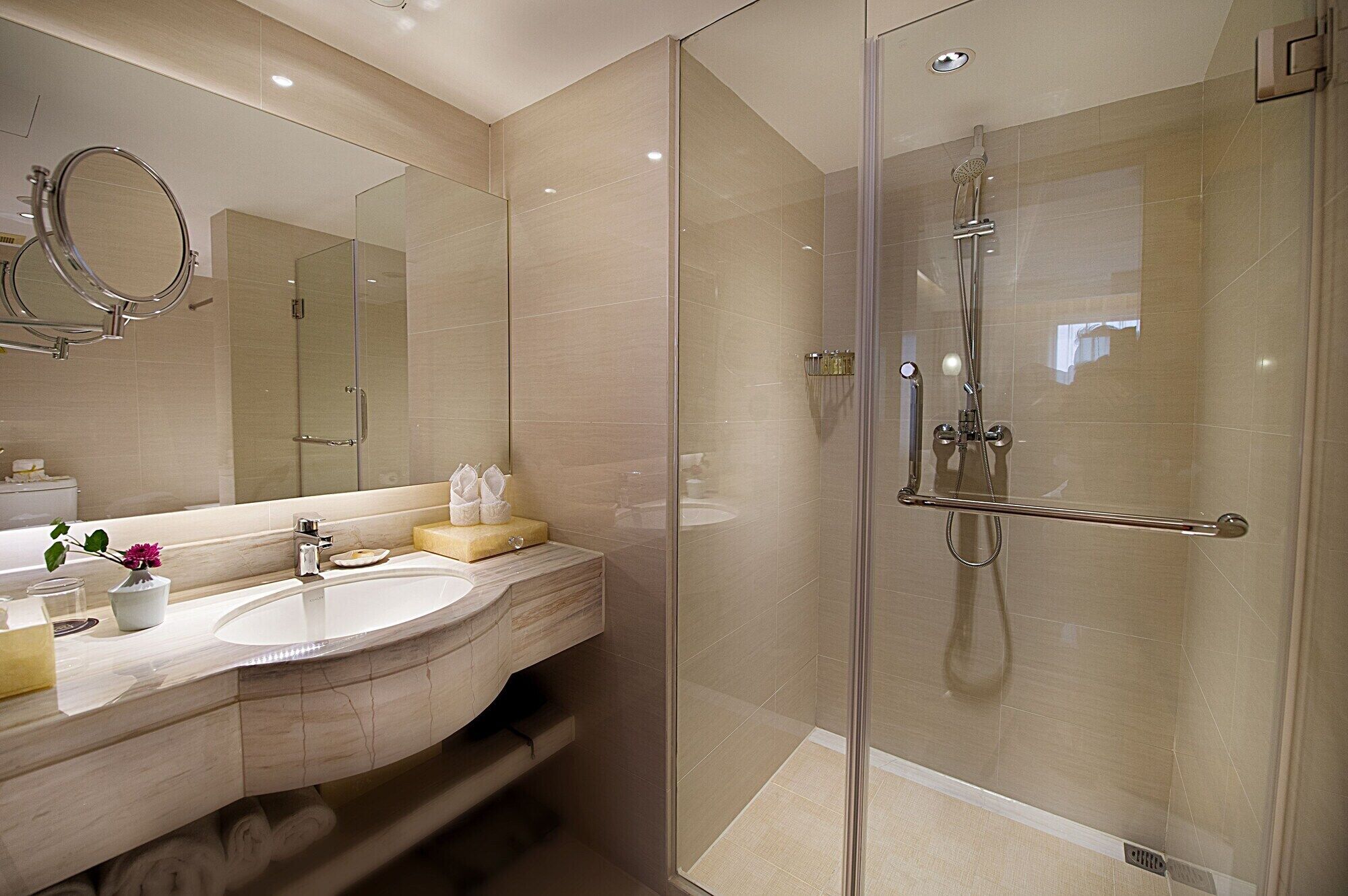 Un baño moderno con ducha de vidrio, tocador con espejo y lavamanos.