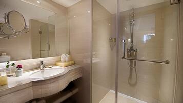 Un baño moderno con ducha de vidrio, tocador con espejo y lavamanos.