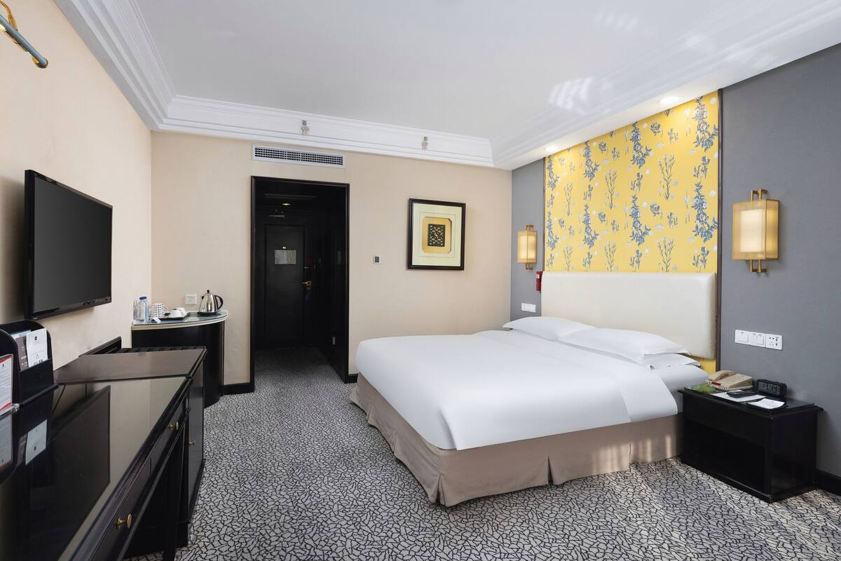 Une chambre d’hôtel avec un lit, une télévision, un bureau et une table de chevet.
