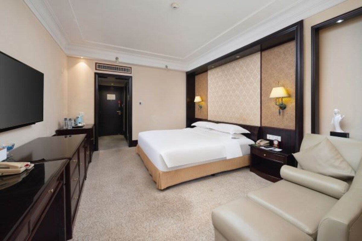 Ein Hotelzimmer mit einem Bett, einem Schreibtisch, einem Stuhl, einem Fernseher und einer Lampe.