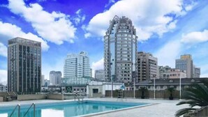 A pool area with a view of a cityscape, including a tall, cylindrical building and several other high-rise buildings. - Grand Metropark Hotel Hangzhou (Hangzhou)