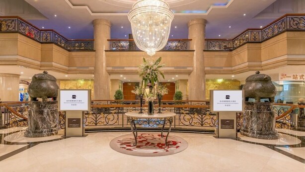 A grand lobby with a large chandelier, marble columns, and a central round table with a floral arrangement. - Grand Metropark Hotel Hangzhou (Hangzhou)