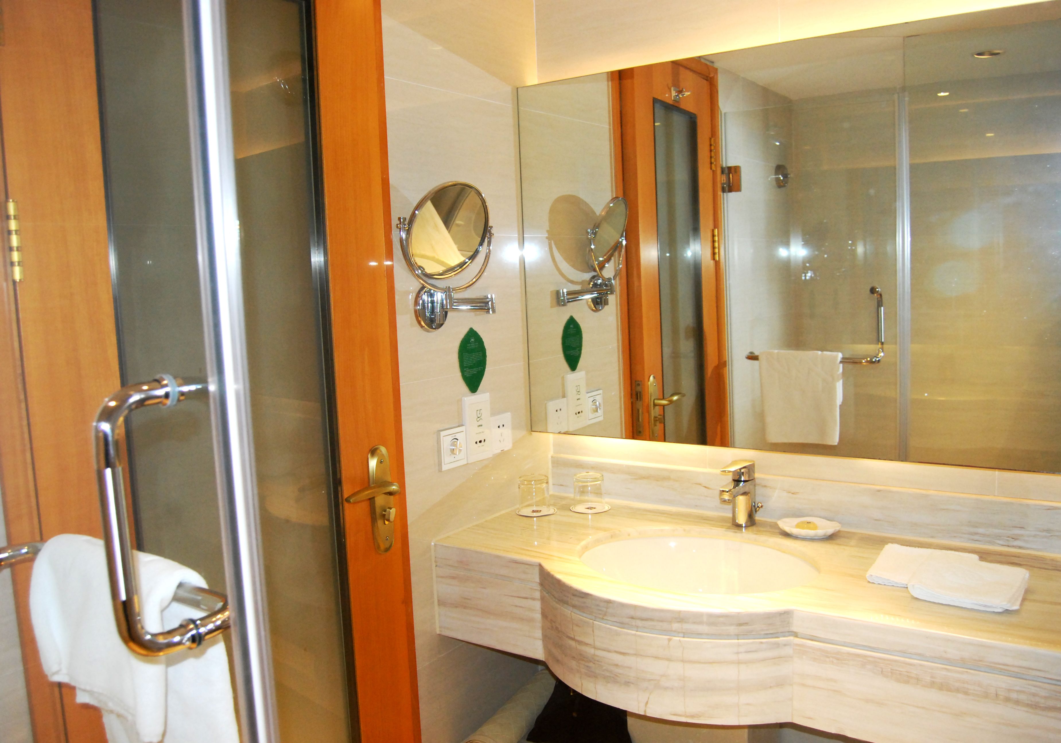 Un bagno moderno con cabina doccia in vetro, lavabo in marmo e un grande specchio.