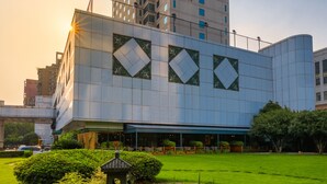 A modern building with a large glass facade and a garden area with rocks and plants. - Grand Metropark Hotel Hangzhou (Hangzhou)