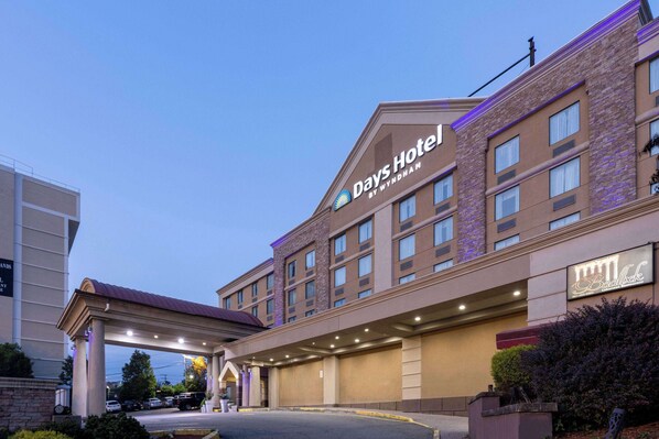 A Days Hotel by Wyndham with a brick facade, multiple windows, and a covered entrance area. - Days Hotel by Wyndham North Bergen /NYC Area (North Bergen)