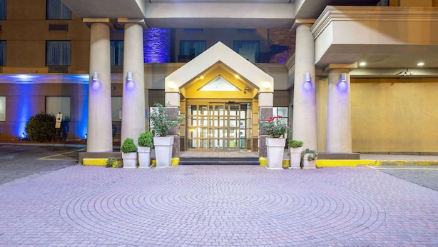A hotel entrance with a central archway, columns, and potted plants. - Days Hotel by Wyndham North Bergen /NYC Area (North Bergen)