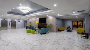 A hotel lobby with marble flooring, a chandelier, seating areas, elevators, and a television. - Days Hotel by Wyndham North Bergen /NYC Area (North Bergen)