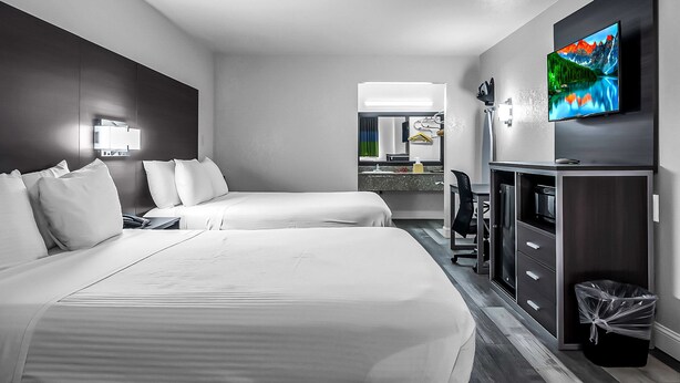 A hotel room with two beds, a desk, a TV, and a bathroom visible through an open door. - SureStay Hotel by Best Western Oklahoma City West (Oklahoma City)