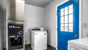 A laundry room with a blue door, a white washing machine, and an ice dispenser. - SureStay Hotel by Best Western Oklahoma City West (Oklahoma City)