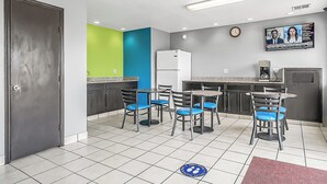 A modern kitchen with a refrigerator, a coffee machine, and a dining area with chairs and a table. - SureStay Hotel by Best Western Oklahoma City West (Oklahoma City)