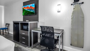 A hotel room with a flat-screen TV mounted on the wall, a desk with a chair, a microwave, and a built-in mini-fridge. - SureStay Hotel by Best Western Oklahoma City West (Oklahoma City)