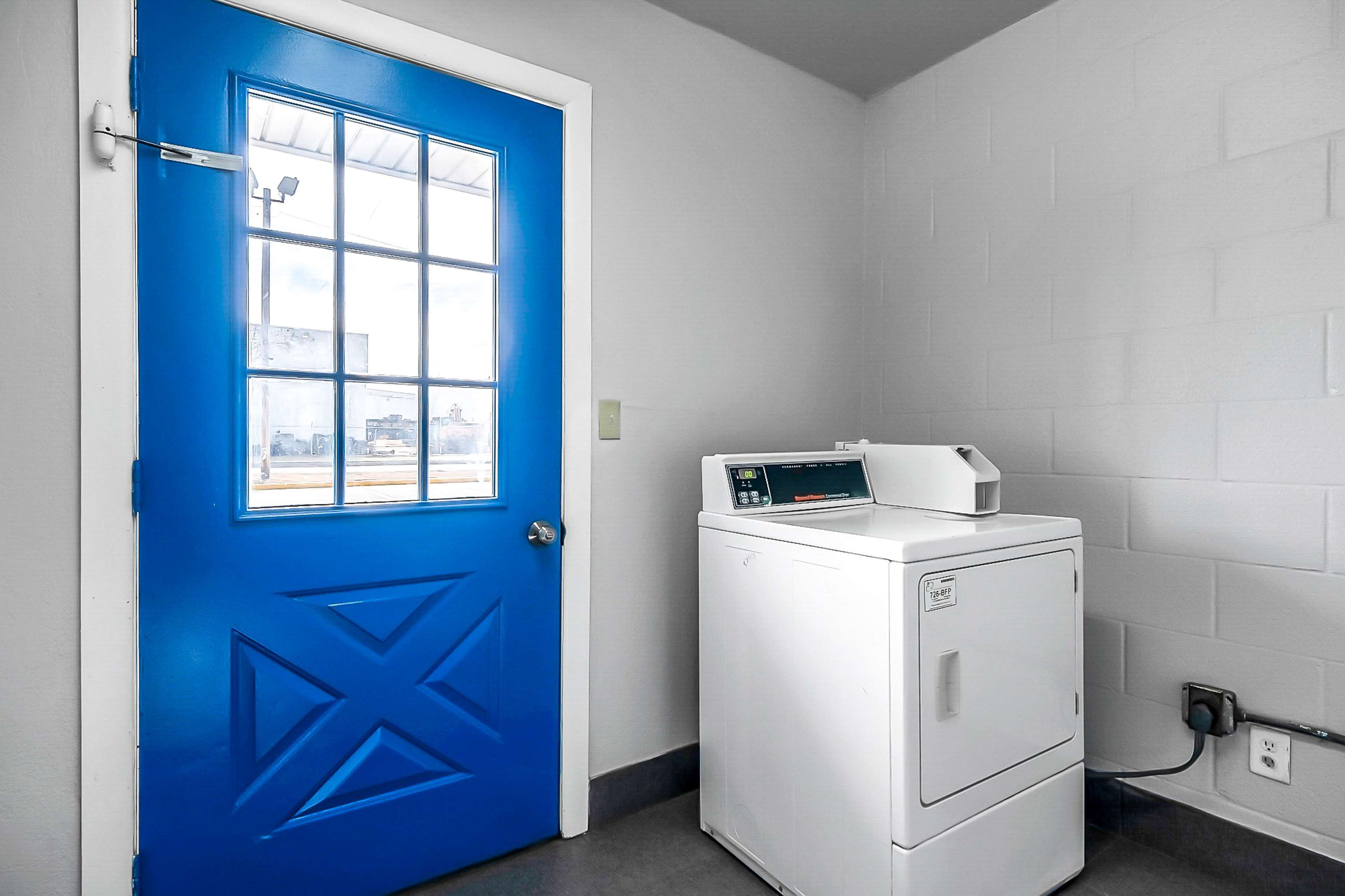 A laundry room with a blue door and a white washing machine.