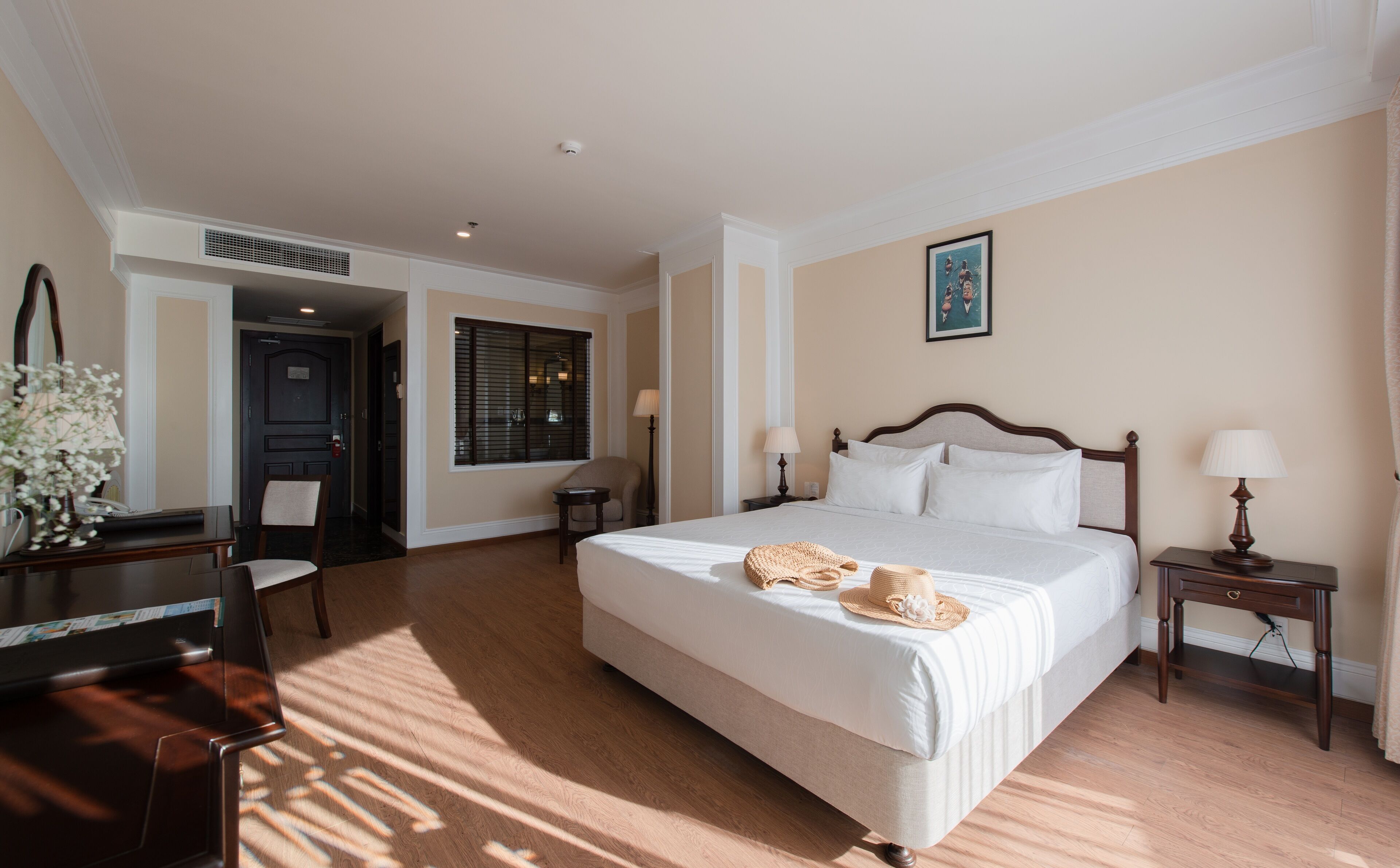 Ein Hotelzimmer mit einem großen Bett, einem Schreibtisch, einem Sessel und einem kleinen Tisch.