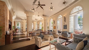 A spacious lobby with high ceilings, large windows, and multiple seating areas.