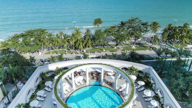 A rooftop pool with a circular design, surrounded by lounge chairs and umbrellas, overlooking a beach and ocean. - Sunrise Nha Trang Beach Hotel & Spa (Nha Trang)