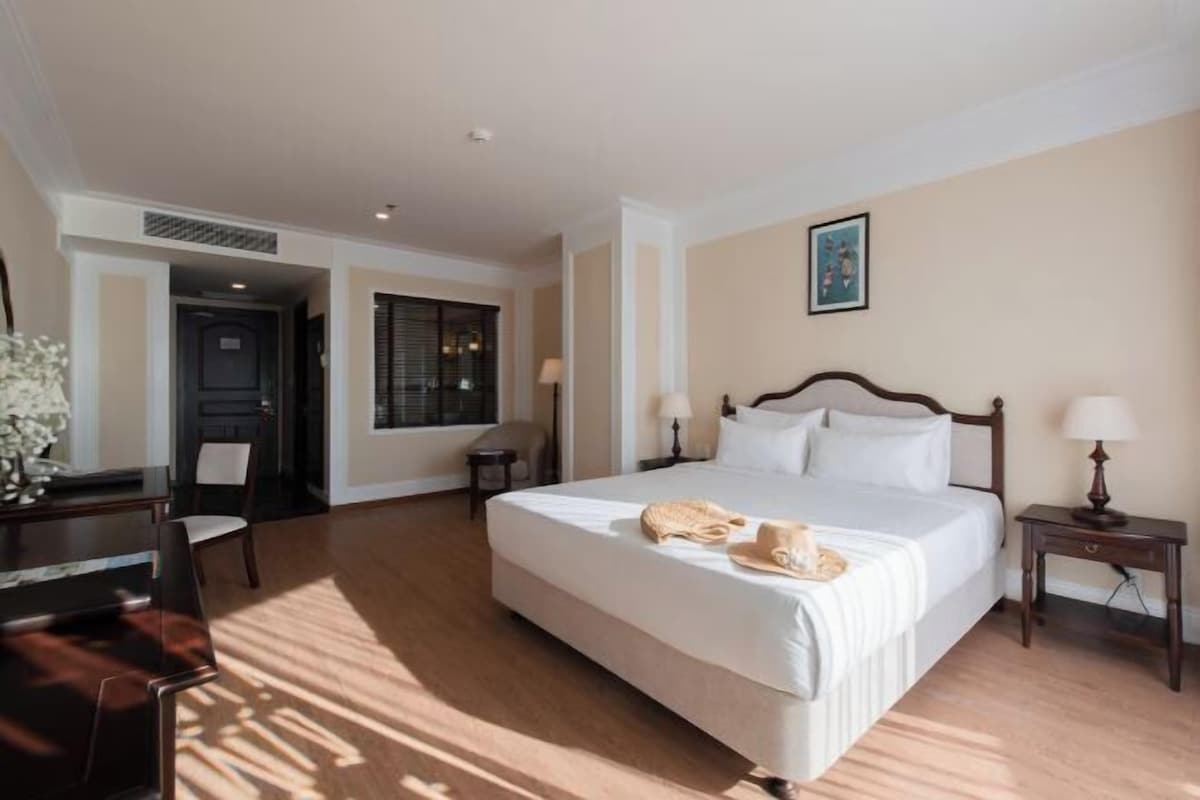 Habitació d'hotel amb un llit gran, una taula de treball, una cadira i una finestra.
