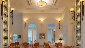Un vestíbulo amplio con techos altos, ventanas arqueadas y mobiliario elegante.