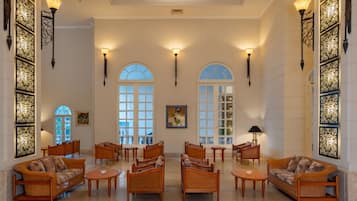 A spacious lobby with high ceilings, arched windows, and elegant furniture.