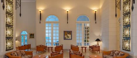 A spacious lobby with high ceilings, arched windows, and elegant furniture.