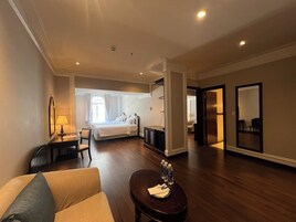 Ett hotellrum med en säng, en sittgrupp med soffa och bord, ett skrivbord och en stor spegel.
