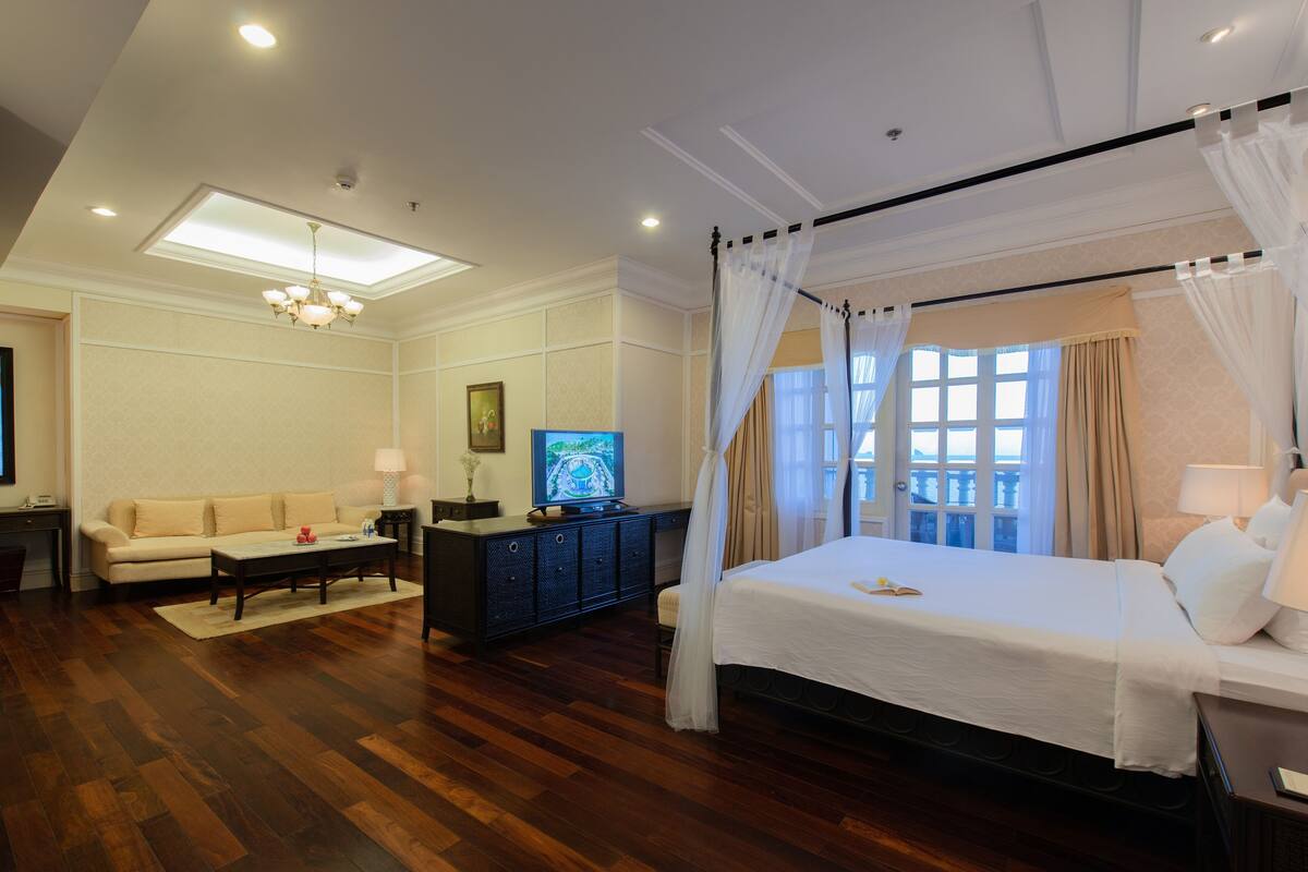 A hotel room with a large bed, a television, a sofa, and a desk.