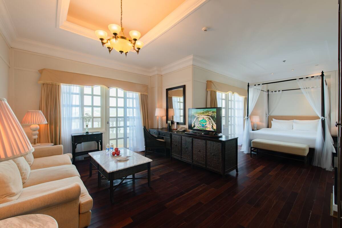 A hotel room with a large bed, a television, a sofa, a coffee table, and a desk.