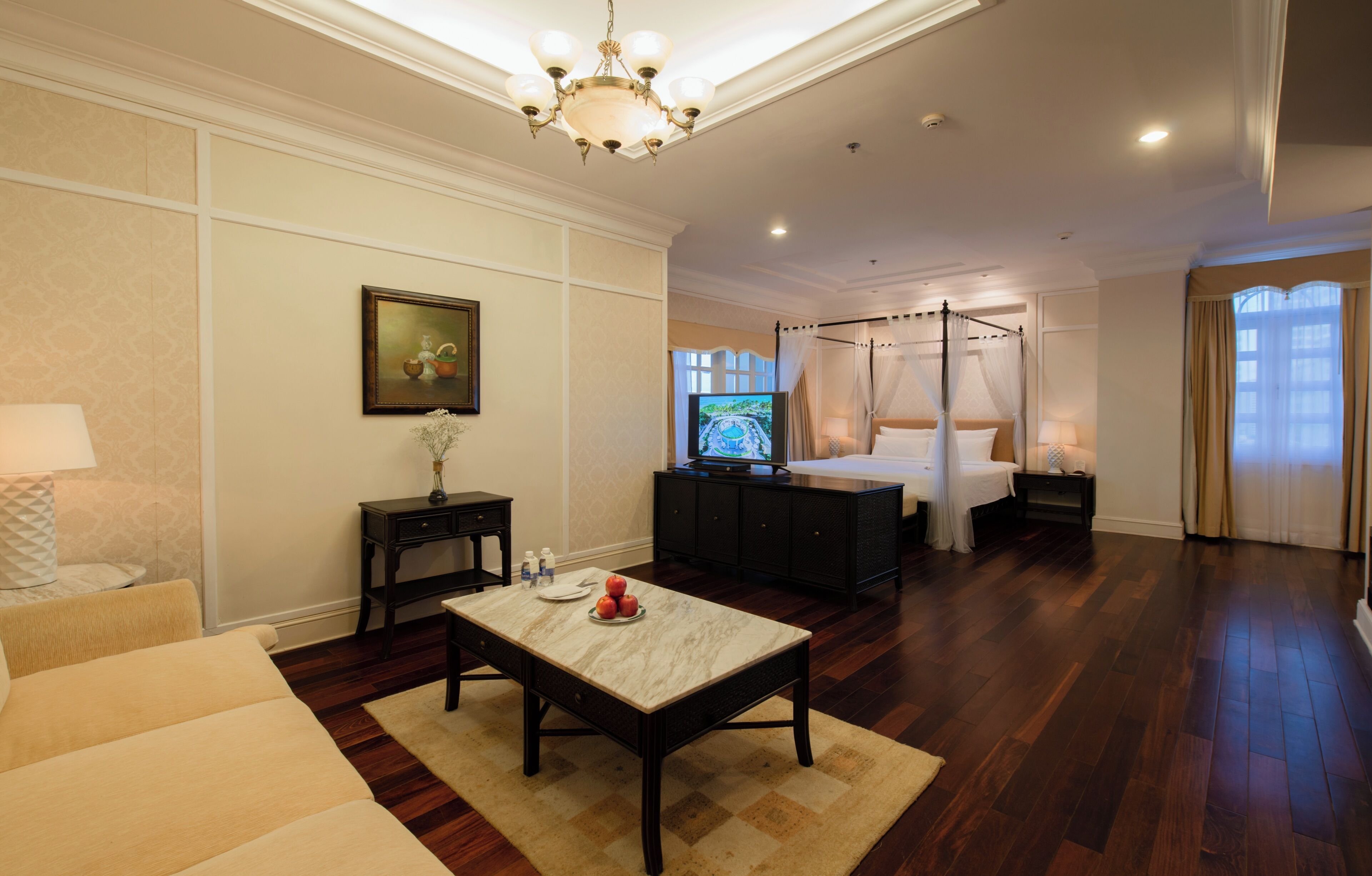 A hotel room with a bed, a TV, a dining table, and a sofa.
