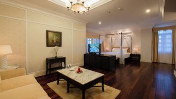 A hotel room with a bed, a TV, a dining table, and a sofa.