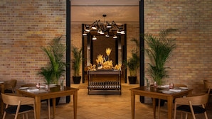 A restaurant with brick walls, wooden tables, and potted plants. - Excellence Riviera Cancun - Adults Only All Inclusive (Puerto Morelos)