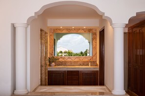 A bathroom with a marble sink, a large mirror, and a view of palm trees through the window.