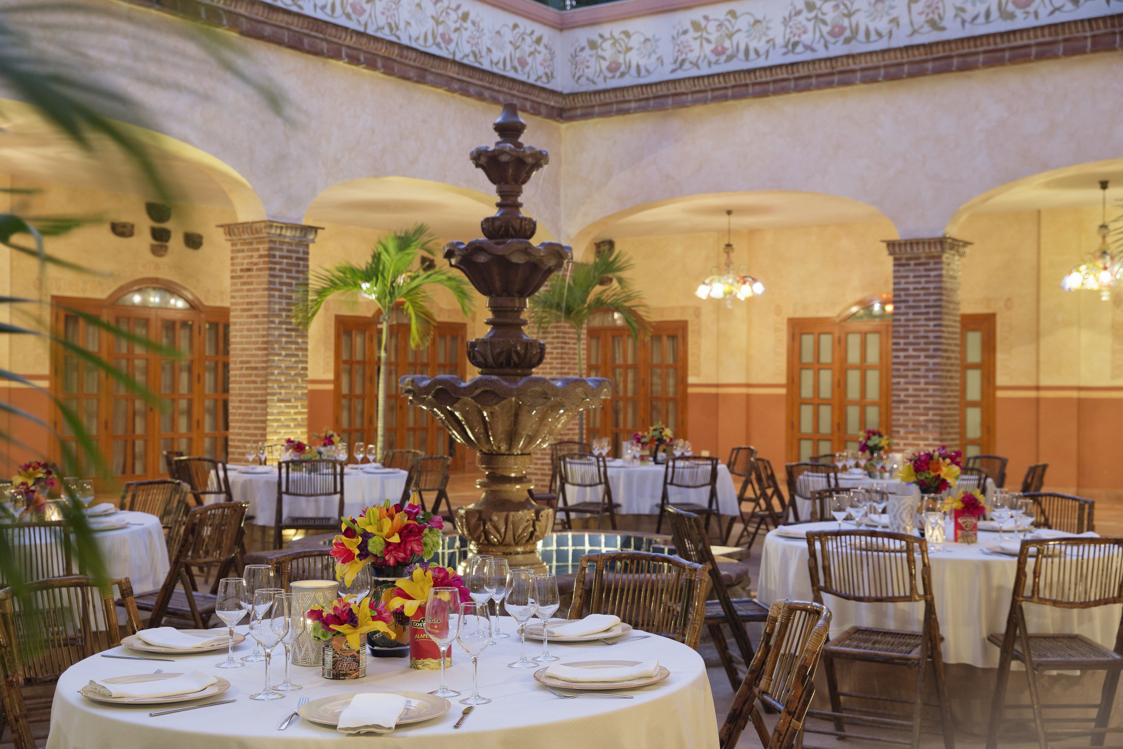 A dining area with round tables, chairs, and a central decorative fountain.