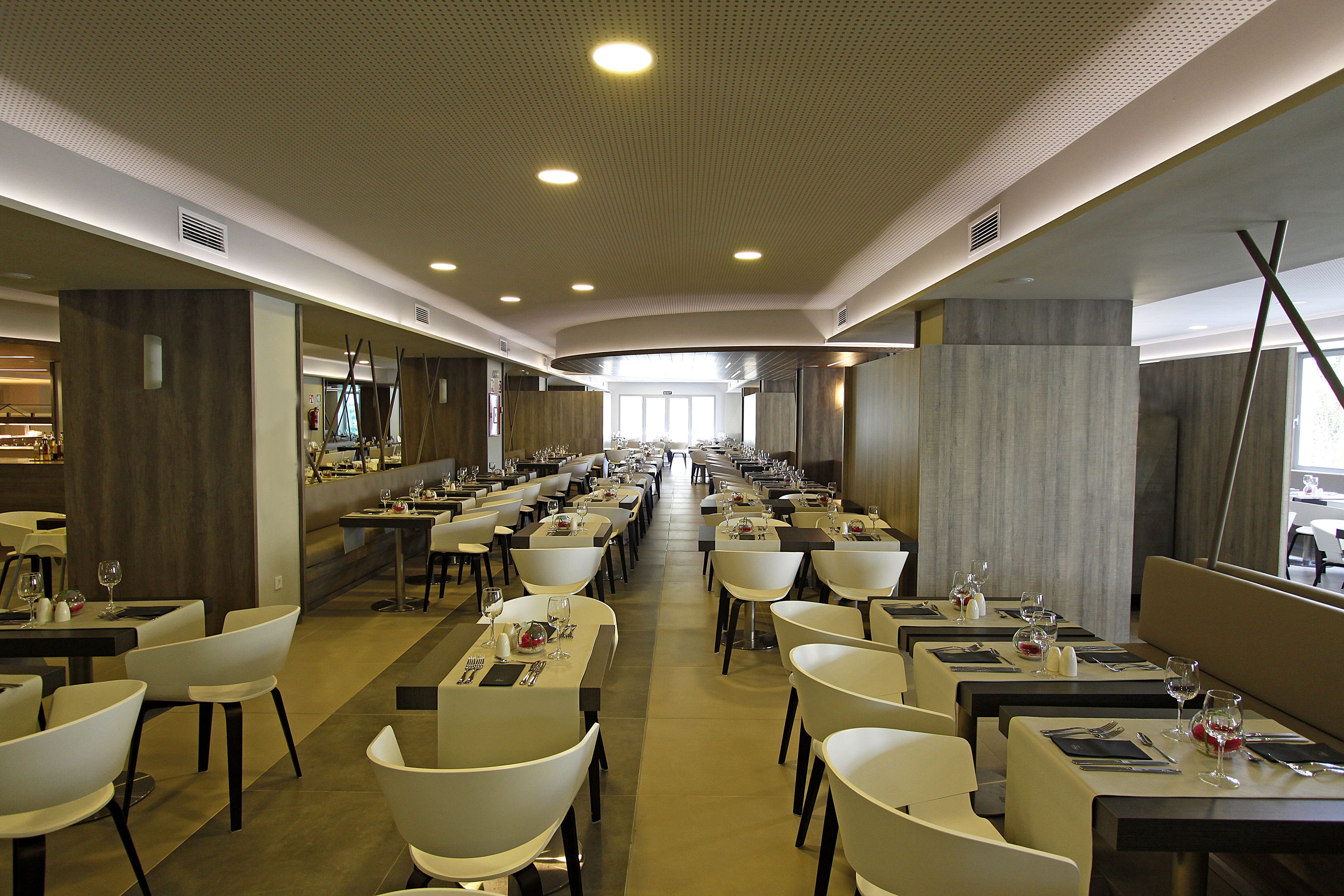 A spacious dining area with multiple tables and chairs, arranged in rows, allowing for easy movement and clear sightlines.