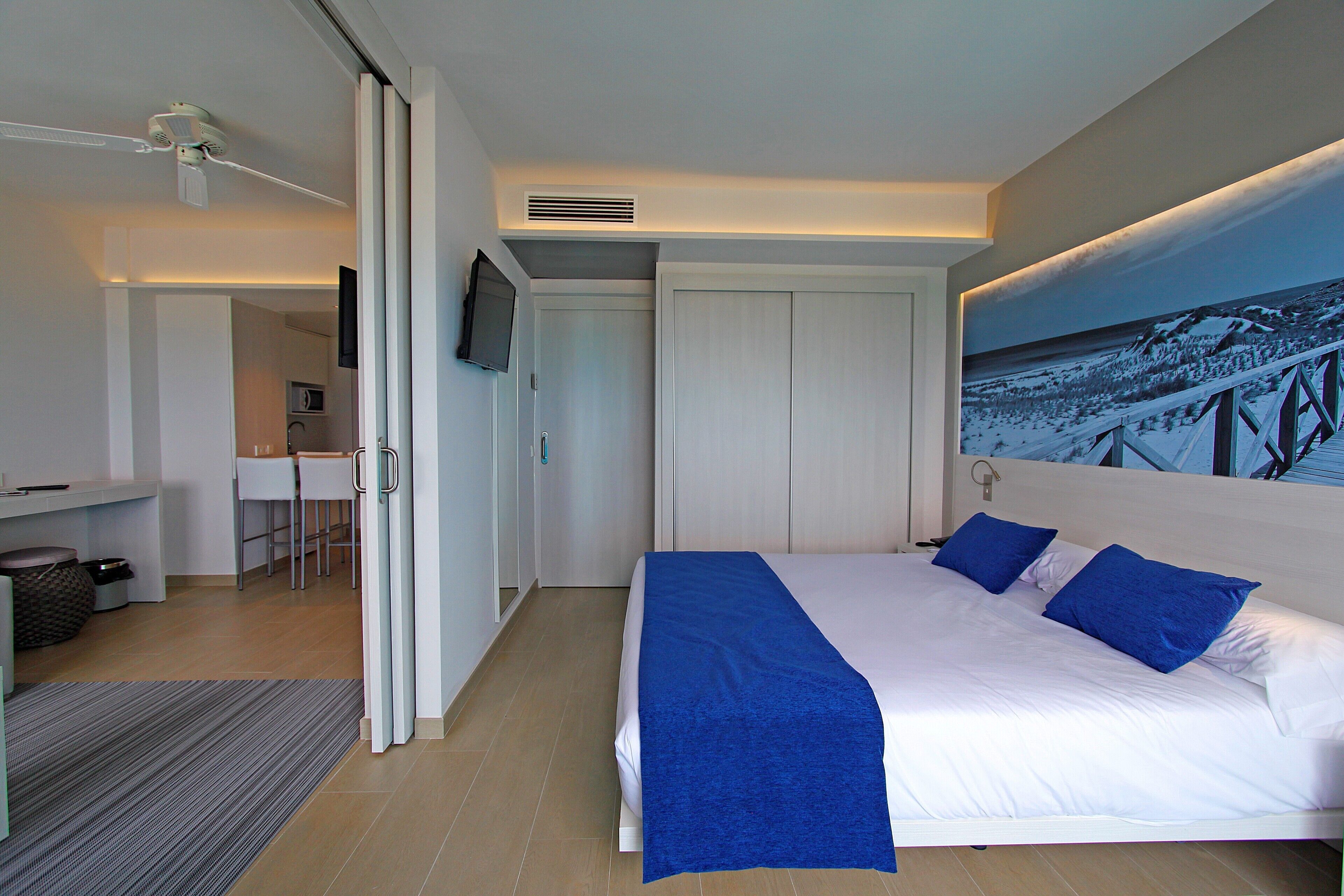 Una habitación de hotel moderna con una cama grande, un escritorio y una televisión.