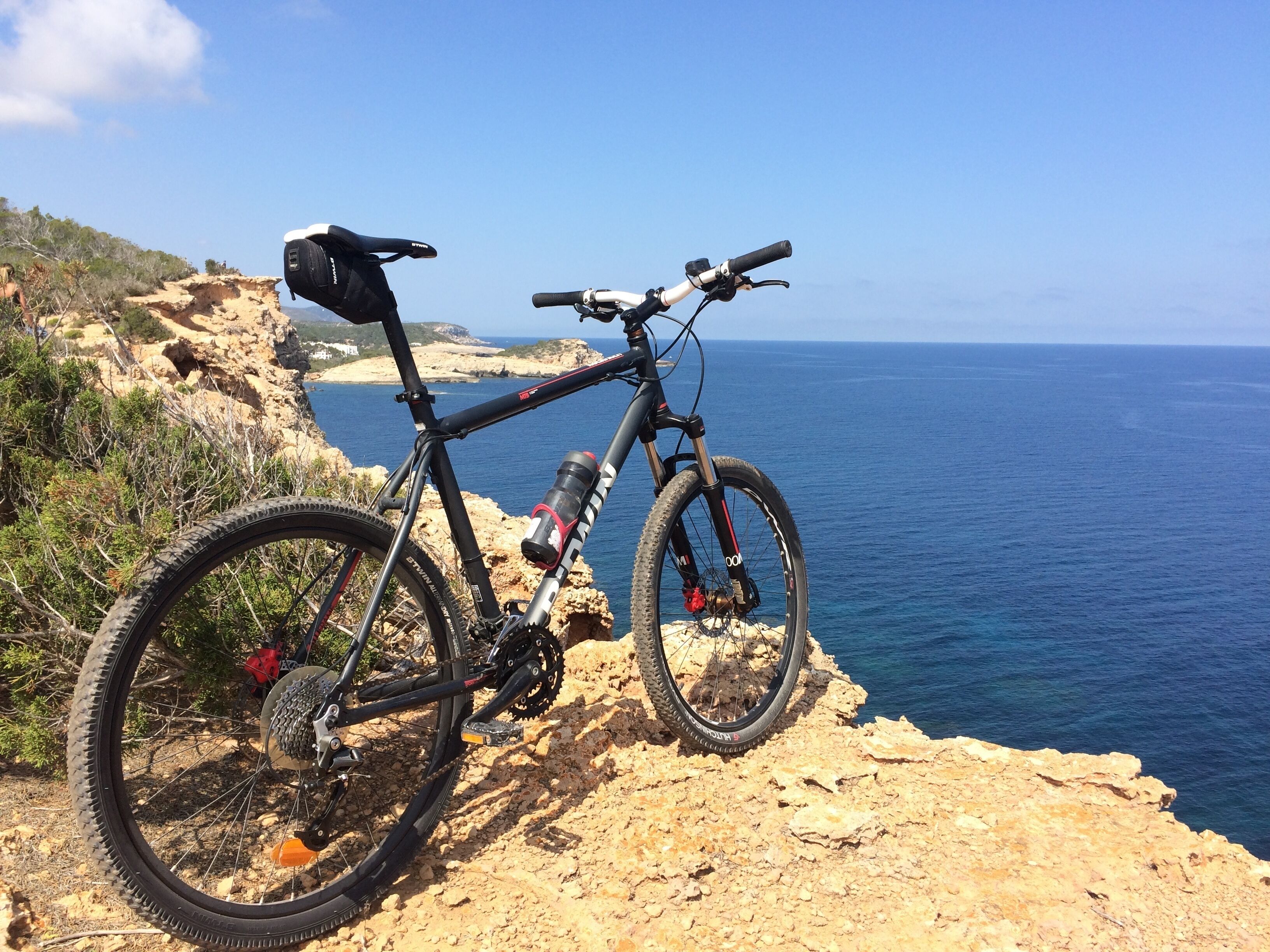 A mountain bike parked on a rocky cliff overlooking the sea.