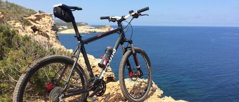 A mountain bike parked on a rocky cliff overlooking the sea.