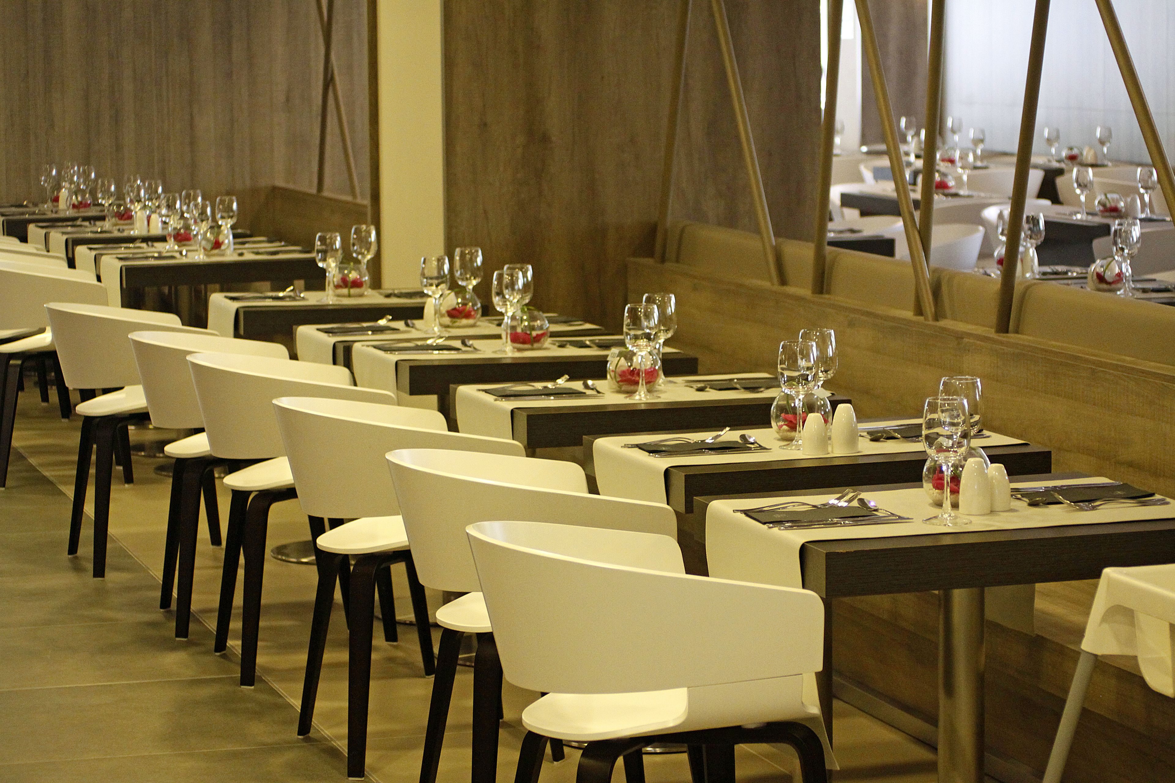 A restaurant with multiple tables set for dining, each with chairs and wine glasses.