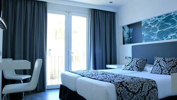 Une chambre d’hôtel avec un lit, deux tables de chevet, un bureau et une chaise.