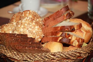 Un panier contenant divers types de pain, notamment du pain complet et des baguettes tranchées.