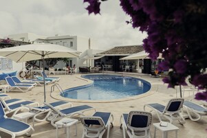 Una piscina al aire libre, sillones reclinables de piscina