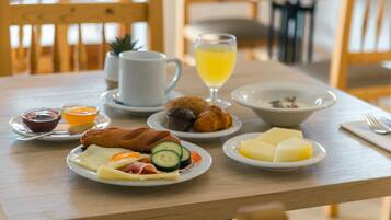 Una mesa de desayuno con platos de comida, un vaso de jugo y una taza.