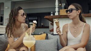 Two people sitting on a grey sofa with a yellow table between them, holding ice cream cones and a drink. - Hotel d´Or (Santanyi)