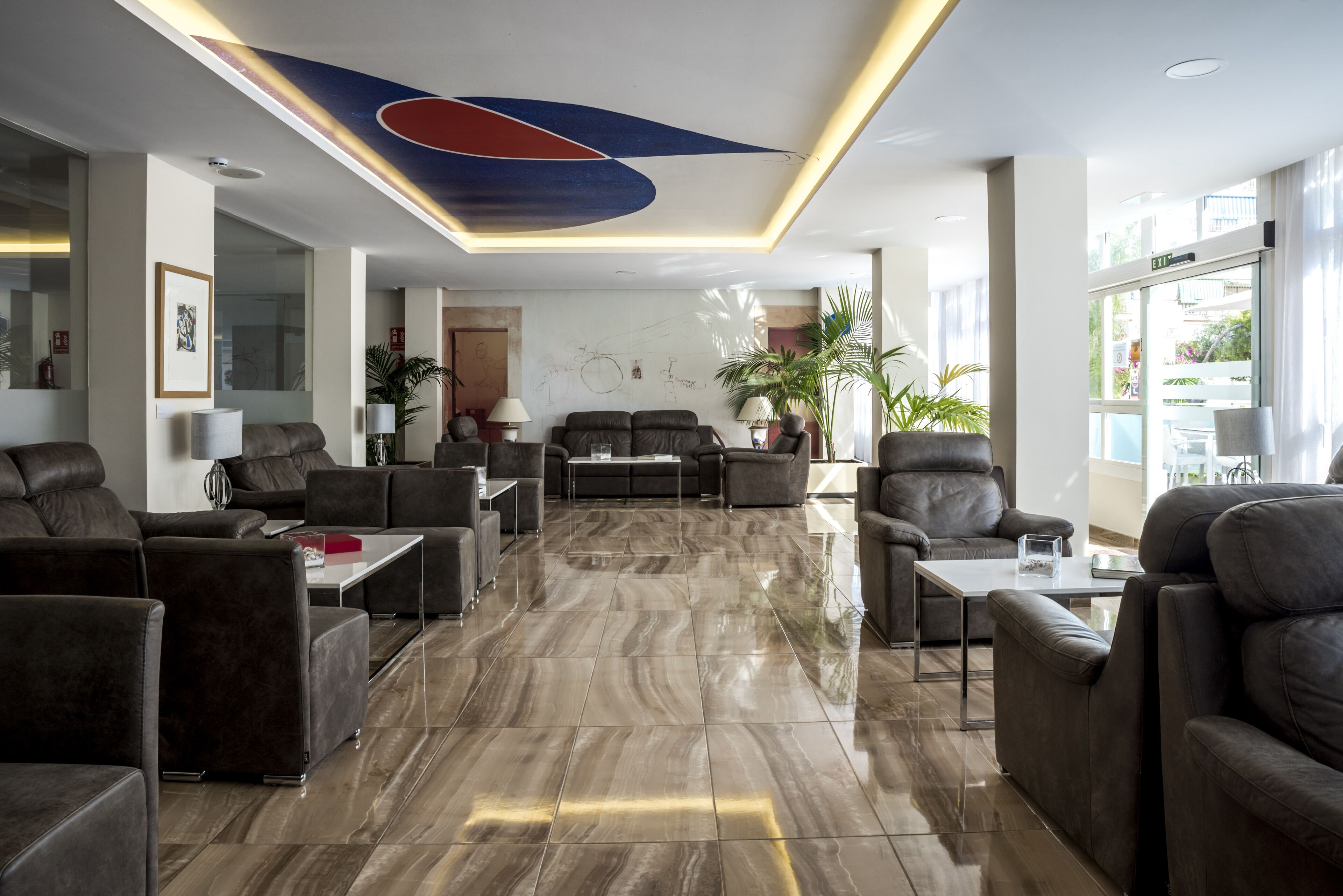 A modern lobby with leather sofas, a marble floor, and a unique ceiling design.