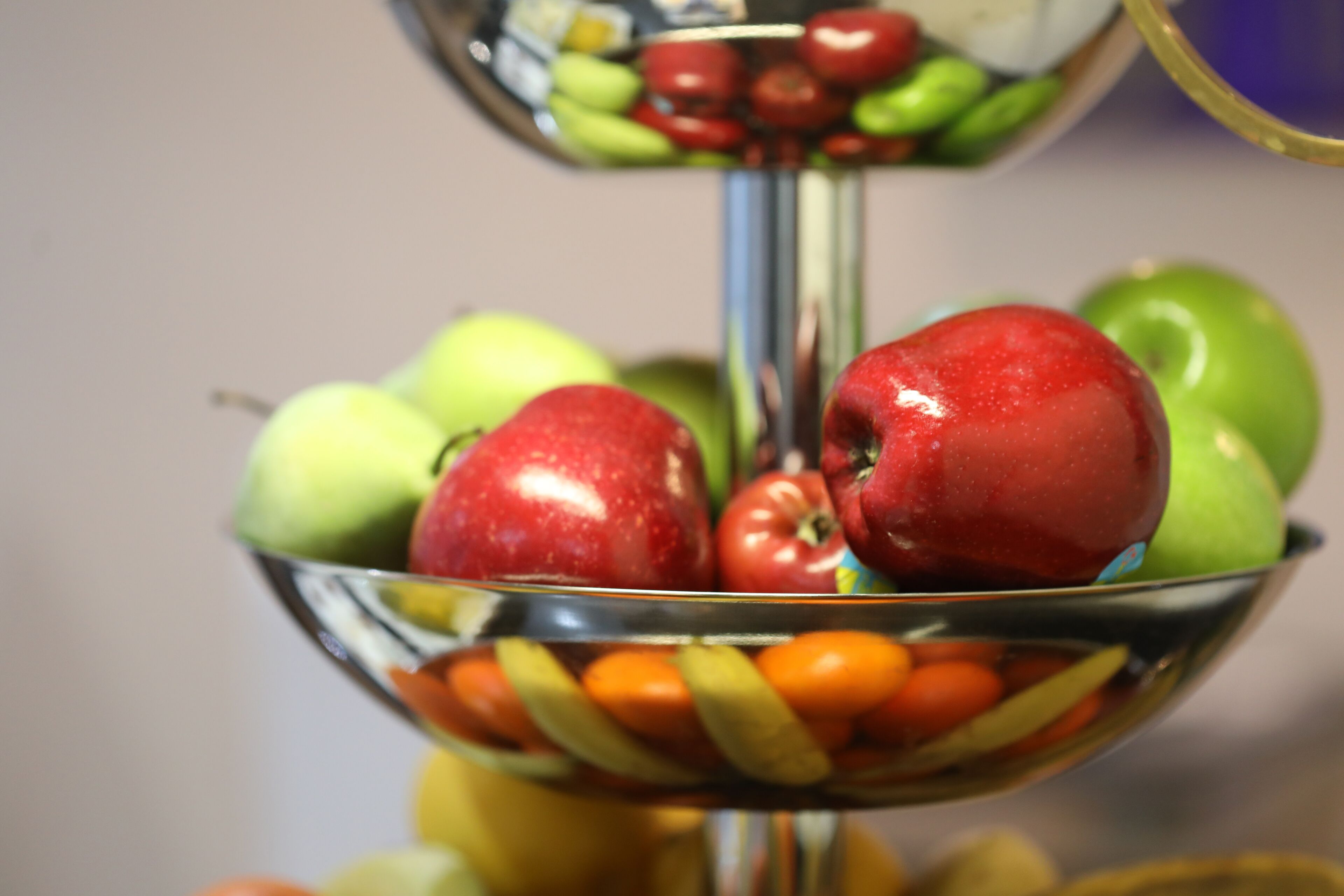 Un frutero con manzanas, naranjas y tomates.