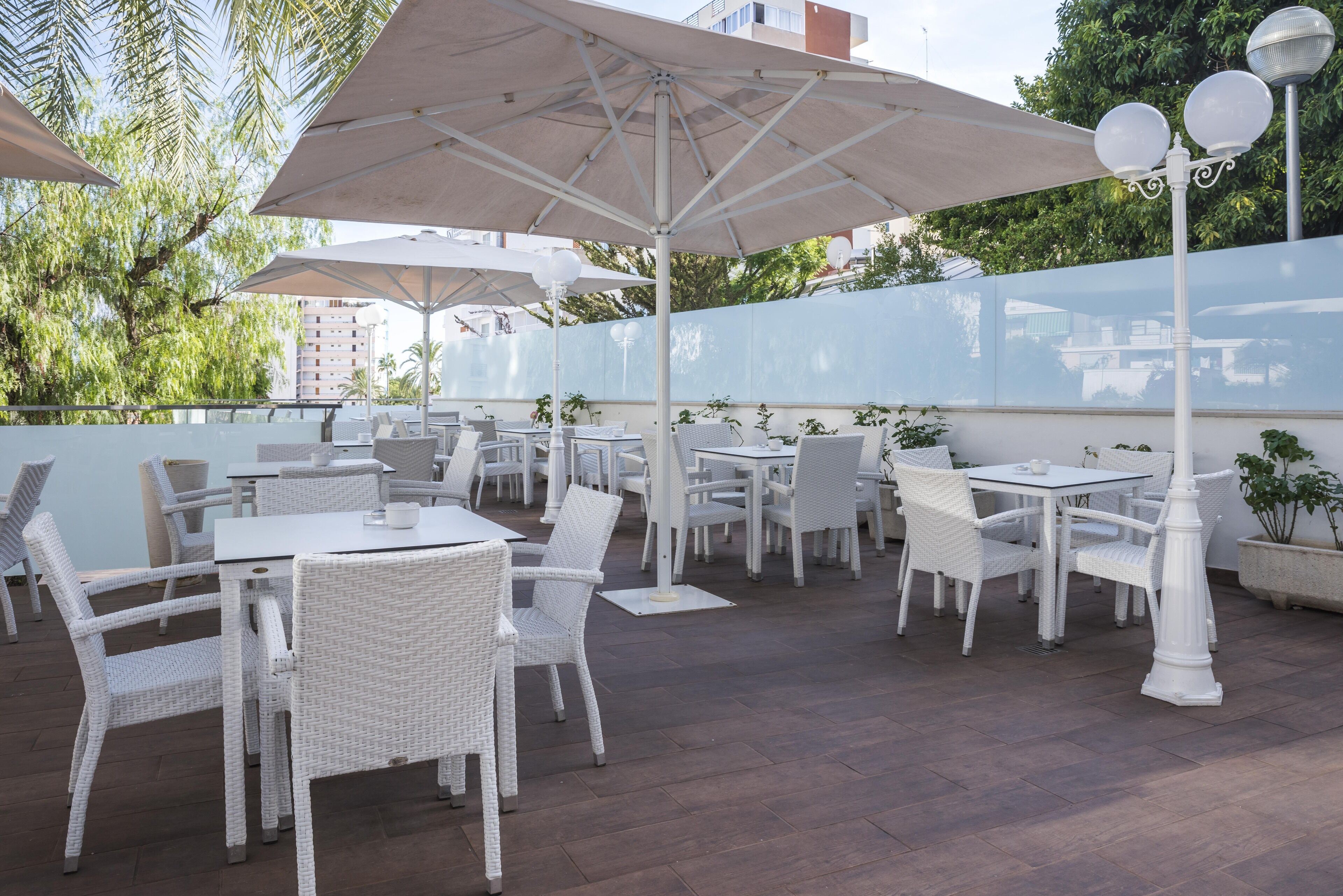 Un patio al aire libre con muebles de mimbre blanco y grandes sombrillas.