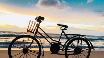 A bicycle on a beach with waves in the background.