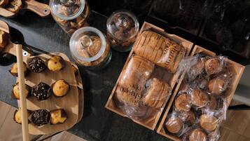 Variedad de productos horneados, como muffins y panes, expuestos en tablas de madera y frascos de vidrio.