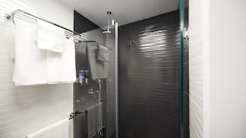 Un baño moderno con cabina de ducha de vidrio, un perchero blanco y una puerta de vidrio.