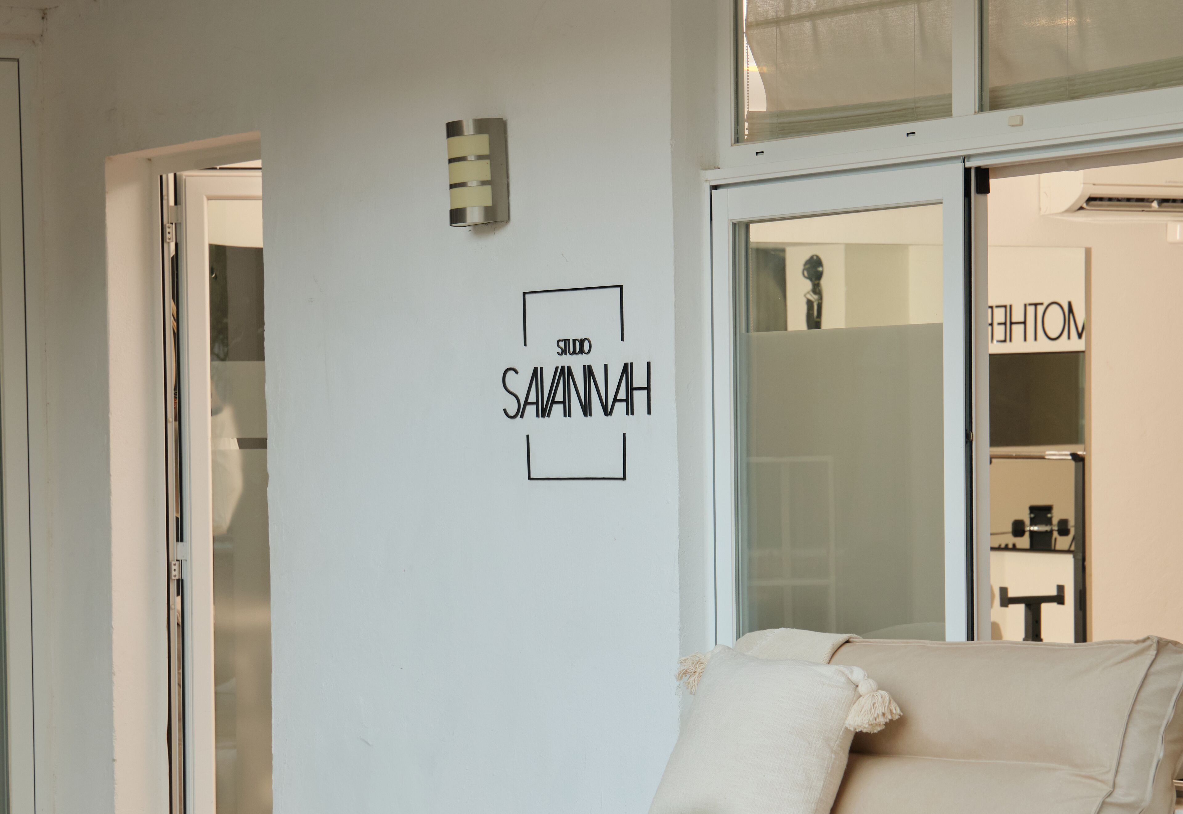 A room with a white wall featuring a logo and a door leading to a bathroom.