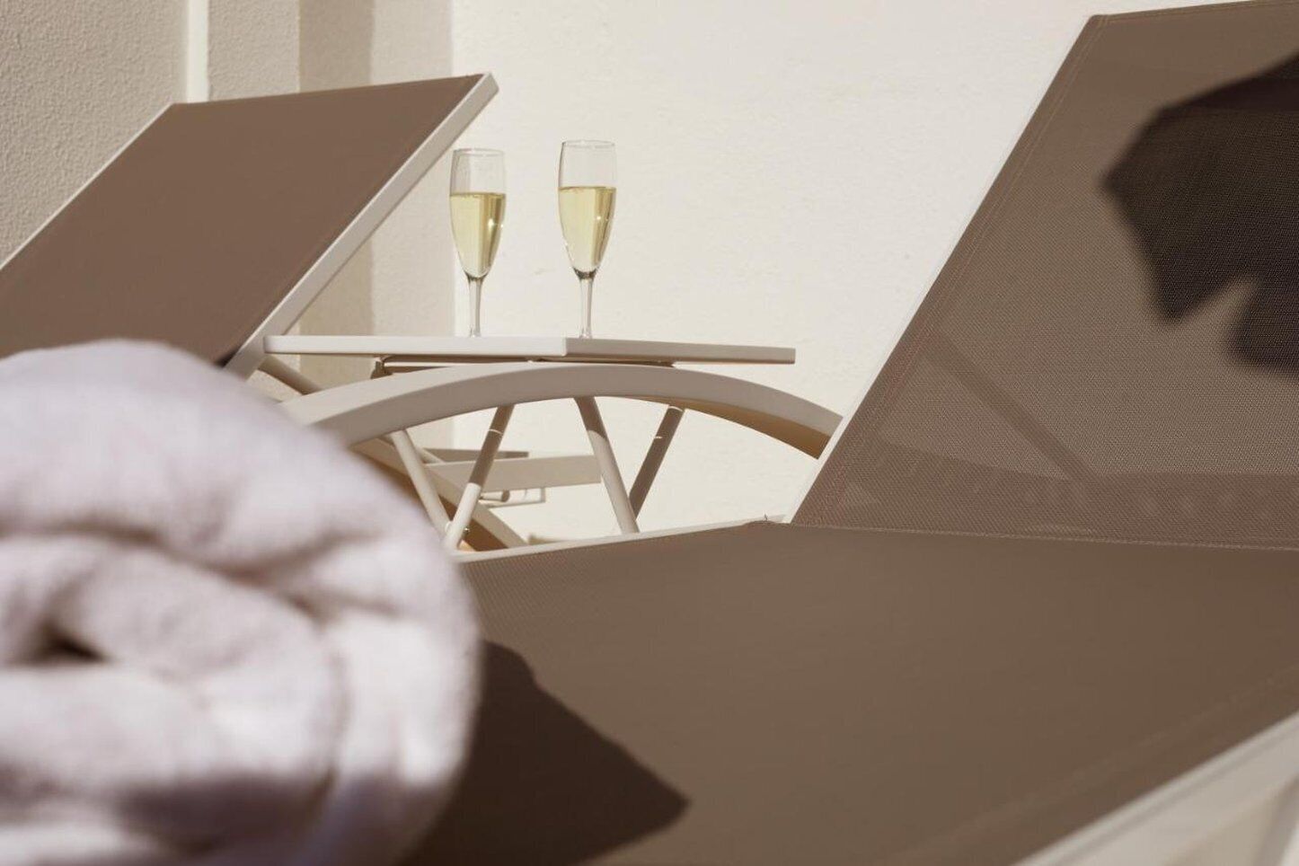 Een ligbed met een tafeltje en twee champagneglazen.